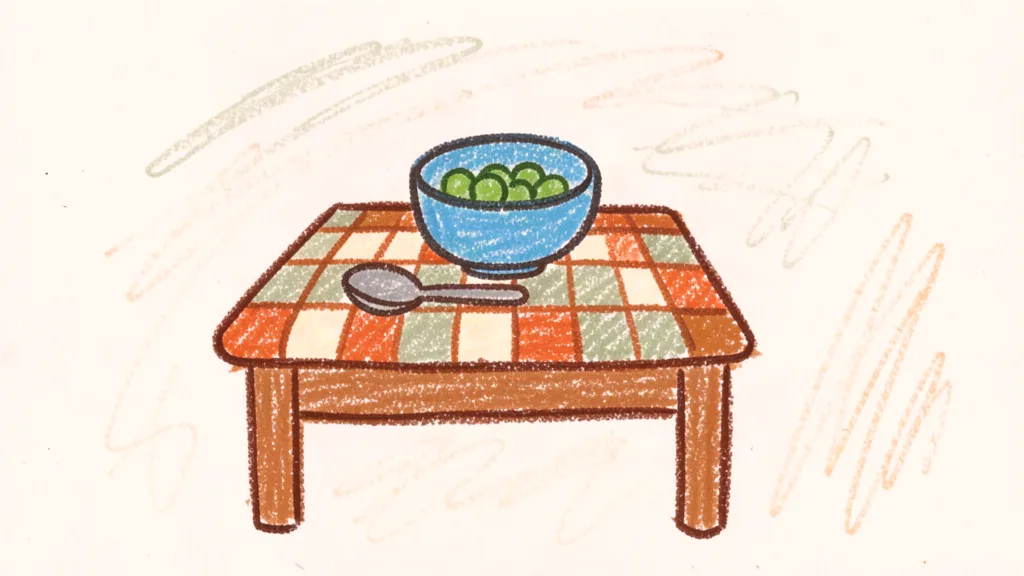 A child's crayon drawing of a small bowl with peas and a spoon on a checkered tablecloth